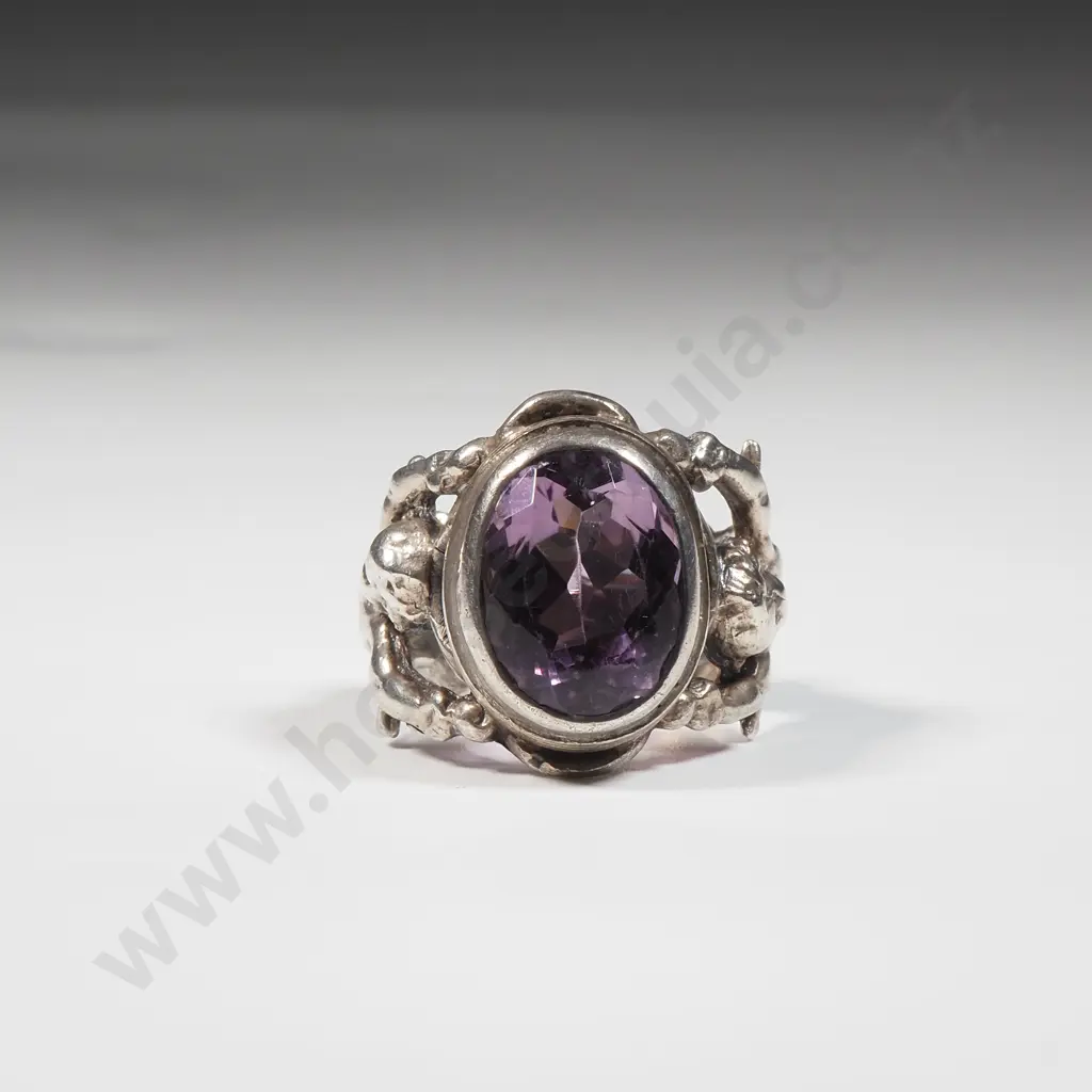Sterling Silver Ring Set With An Amethyst Coloured Stone In An Ornate Frame With Cupids Image 1++